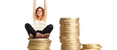 young woman doing a winner gesture sitting on a coins pile