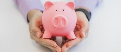Businessman holding pink piggy bank, isolated on white background.