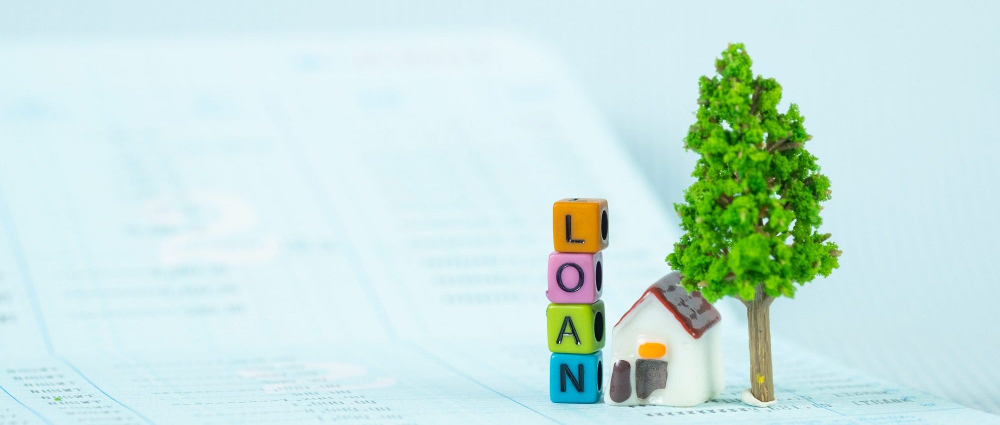 LOAN text and small model house and little tree with notebook, savings banking, loan for house and real estate concept idea.
