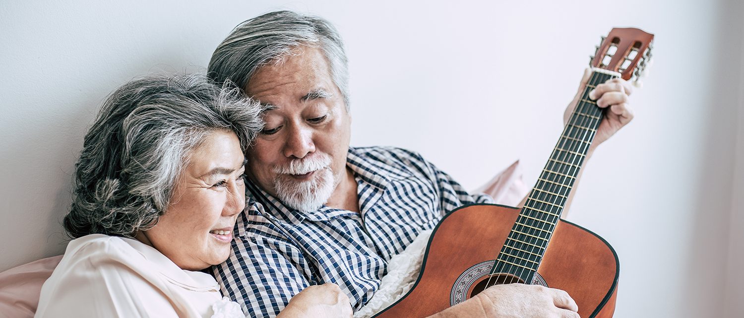 Senior couple relax playing acoustic guitar in bed room