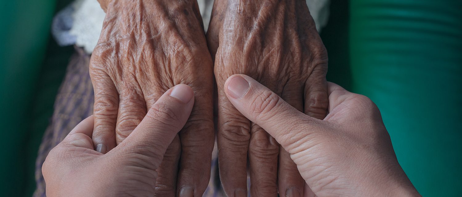 Young woman holding an elderly woman's hand.